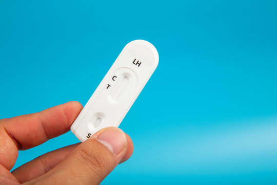 Man hand with holding Pregnant test kit on blue background.