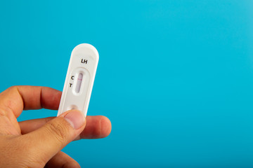 Man hand with holding Pregnant test kit on blue background.