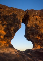 Obraz premium Sunset view trhouogh the rock hole (Pedra furada), in Portal da chapada, a trourist attraction in Chapada das mesas, Brazil