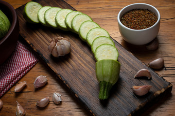  zucchini slices on wooden board garlic pepper and seasonings © Alejandro Piorun