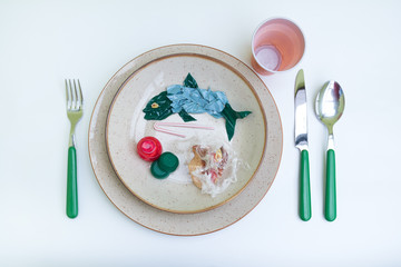 Plastic pollution comes to our tables. Plastic and microplastics pollute the sea and We eat fish that have absorbed plastic. Dish with fish and side dishes made of plastic. Isolated on white.