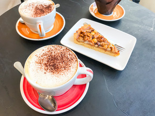 Black stone bistro table with cups of cappuccino and pastries.