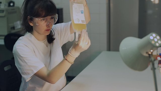 Healthcare examines a plastic bag with blood plasma at center for transfusiology and hematology