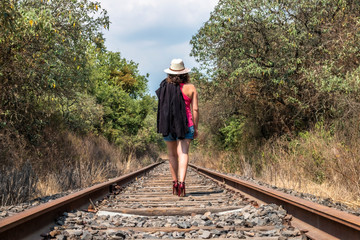 casual young woman in pink blouse and shorts walking on a railway