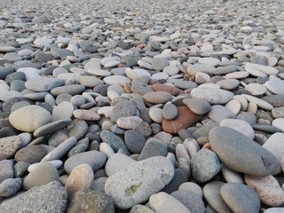 Perspective of rounded sea pebble stones & rock on beach natural abstract pebble texture background. Small multicolor river pebble rock stones. Close up colorful rock stones or gravel on ocean coast.