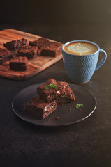 Brownies with Latte art coffee on dark table and wooden cutting board and copy space