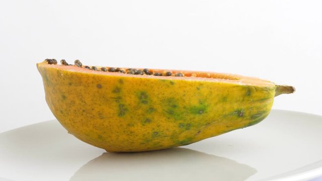 Ripe half cut papaya fruit. Rotating on white background