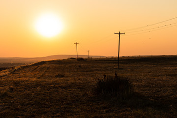 Blazing hot sun over a western desert terrain with telephone poles