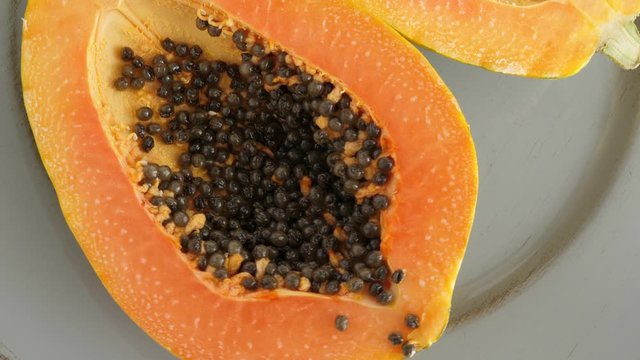 Top view of ripe half cut papaya. Rotating. Food background