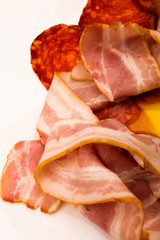 Slices of sausage and bacon on a white background. Close up.