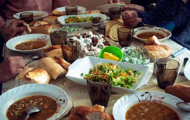 Crowded muslim family having a dinner together gathered around a table eating food