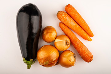 Juicy onions, ripe eggplant and orange carrots on a white background. Close up.