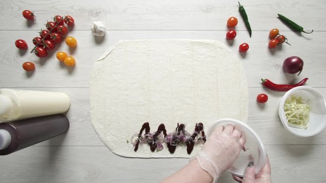Chef hands in white gloves puts chicken and french fries on doner kebab shawarma in pita or lavash. Cooking shawarma with chicken, french fries, cheese and vegetable