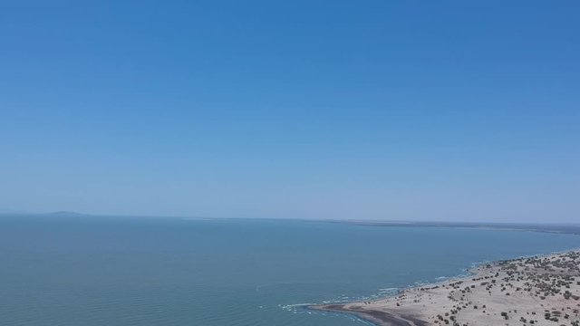 Lake Turkana Kenya Aerial view of the sky, lake, and beach with small palm trees and small waves on the beach