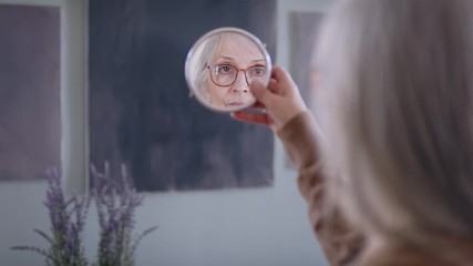 Sad and depressed woman looking in mirror indoors, mental health concept. - Powered by Adobe