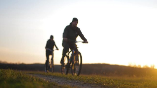 Couple tourists ride on bike on the road. Two silhouettes of cyclists on a sunset background. Sport and active life concept sunset time.