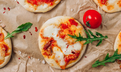 Pizzete. Home baked mini pizzas bolognese. Tomato sauce ,mozzarella cheese and minced meat. Rustic paper table. Stay at home concept