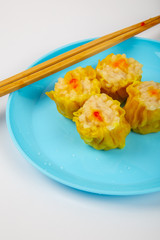 Siu Mai - Chinese steamed pork dumplings on blue plate isolated on white background.