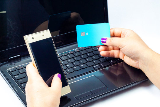 Woman Holding A Golden Cell Phone With A Blue Card On Top Of A Notebook