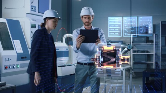 Factory Office Facility: Chief Engineer Holds Tablet Computer, Shows Augmented Reality Model of an Electric Generator to a Female Project Manager. Modern Industry 4.0 Research and Development Center.