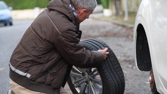 Man checking flat tire with sharp object inside. Slow motion