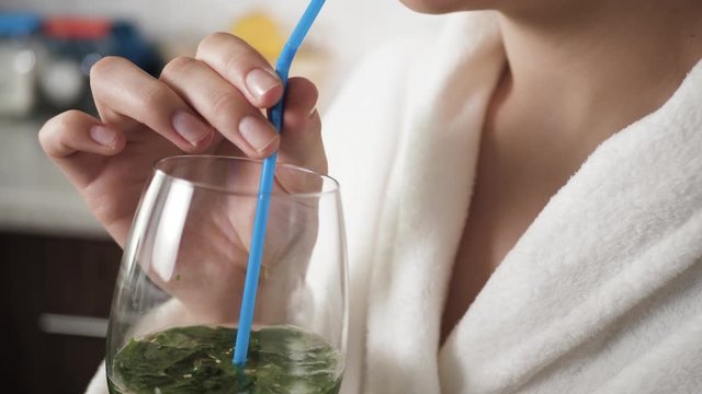 Girl is drinking mojito. Female hands bring mojito glass to their faces and drink through straw. Close-up