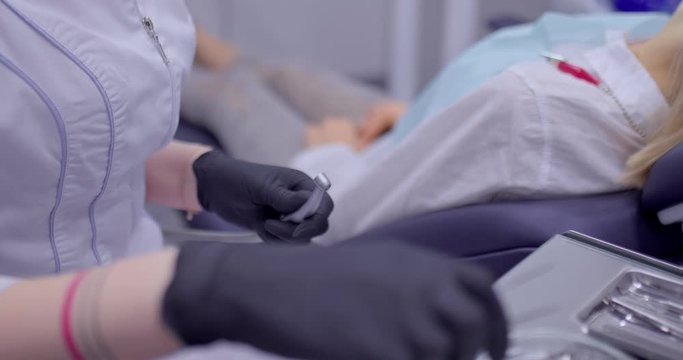 Doctor picks up a drill with tweezers and inserts it into the drill. Dentist drills the patient's tooth, treat the tooth. Professional equipment and tools of the dentist. Close-up.