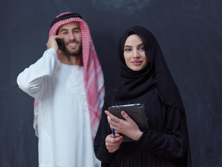 muslim couple using modern technology in front of black chalkboard