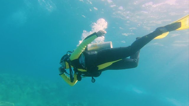 beginner PADI diver holds her nose to equalize as she submerges