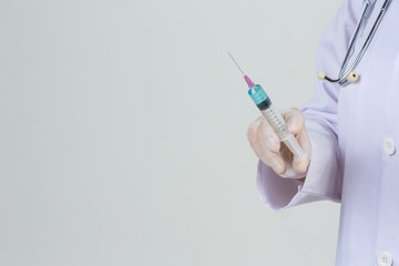 Young doctor is  holding  hypodermic syringe with  vaccine vial  rubber gloves on gray background.
