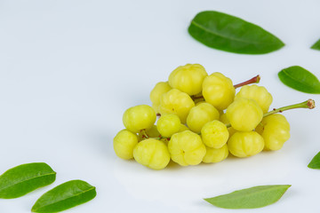 Fresh star gooseberry fruits with leaves ready to eat isolated from the tree on white background.