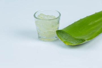 Jel of aloe vera in a glass with aloe vera leave is near together on white background.