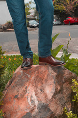 Obraz premium Outdoor photo of a man with brogue shoes standing on a rocky boulder