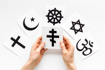 Choose religion concept. Hands with Orthodox cross near world religions symbols on white background...