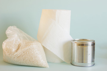Donation food and charity concept. Pack of rice, toilet paper and canned food on blue background.