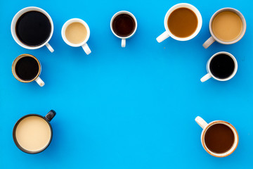 Different cups of coffee on blue table top-down space for text