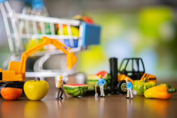 Miniature people of worker in farm loading fresh fruits and vegetable to supermarket warehouse . Fresh food business concept