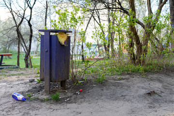 Obraz premium Full trash can and bottle on the ground