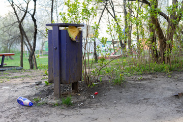 Full trash can and bottle on the ground