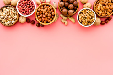 Obraz na płótnie Canvas Nuts set in bowls on pink background top-down frame copy space mockup