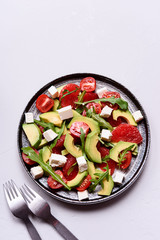 Vegetarian salad with avocado, grapefruit, tomato, feta cheese and arugula. Healthy nutrition. Selective focus