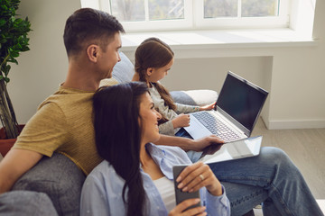 Happy family using laptop together while sitting in room.