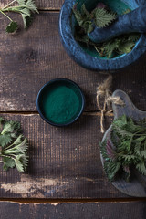 Fresh stinging nettle leaves on wooden table.Urtica dioica oil with spirulina powder, a healthy supplement to improve health.
