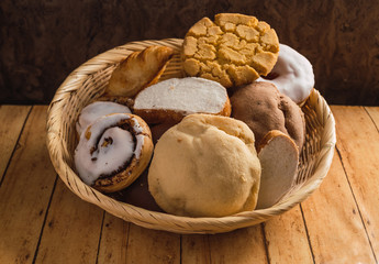Bread basket, typical of the peoples of Mexico, with sweet bread such as conchas, rebanadas, cuernitos, cinnamon rolls, polvorones, on a wooden table.
Something excessively typical in Mexico.