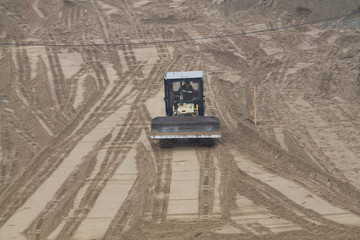 yellow bulldozer on a sandy surface on construction site territory