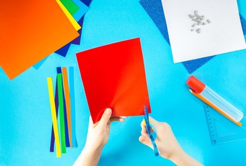 DIY. The creative process. Children's hands cut out various shapes from colored bright paper....