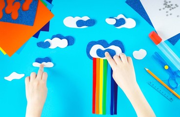 The creative process. Child's hands stick clouds and a rainbow of bright colored paper. Lessons...