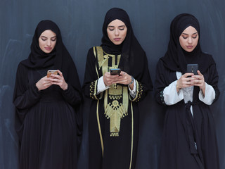 muslim women using mobile phone in front of black chalkboard