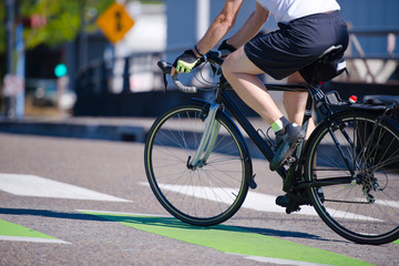 Fototapeta na wymiar Man rides a bicycle crossing a city street preferring an active lifestyle