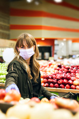 Woman in a face mask wearing latex gloves while shopping in a supermarket during coronavirus quarantine